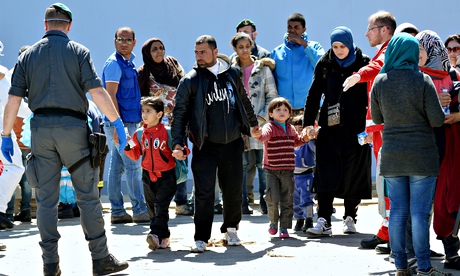 Rescued migrants disembark from the Ital