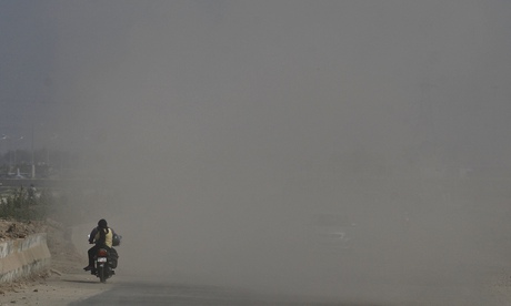 An Indian couple rides a motorcycle through a road in New Delhi
