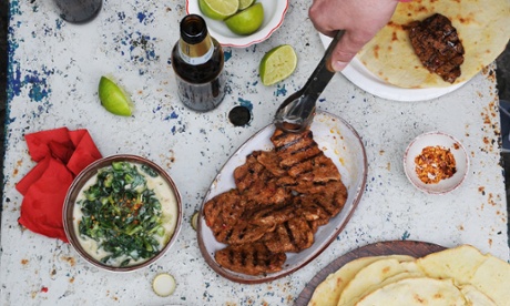 jerk chicken and rotis being served by a man holding tongs