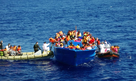 A photo taken by the Migrant Offshore Aid Station shows the Italian Navy (let) helping refugees to climb on their boat in the Mediterranean. 