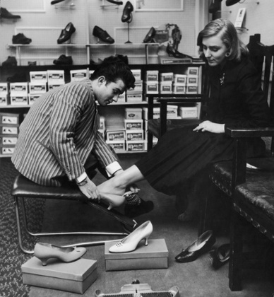 Julian helps a customer try on a new pair of shoes at a shop in Surrey. 