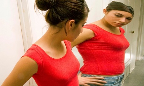 Eating disorder: a slim teenage girl sees herself as overweight in the mirror
