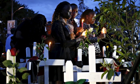 Kenyans hold candles next to wooden crosses