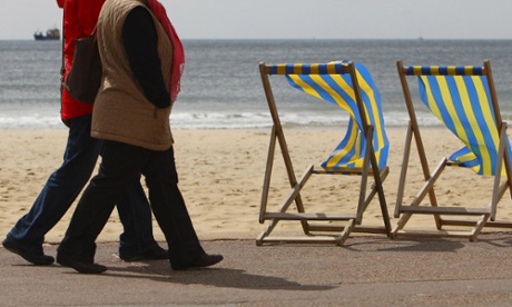 Pensioners walk along a beach promenade.