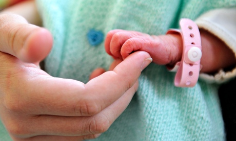 A new-born baby holding the finger of its mother