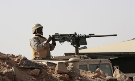 A Saudi soldier sits on top of an armoured vehicle as he aims his weapons on the border with Yemen, at a military point in Najran, Saudi Arabia.