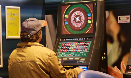 A customer playing roulette on a fixed odds betting terminal in a betting shop in Slough