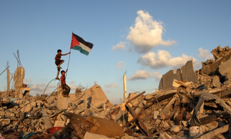 Palestinian children place their national flag on the rubble of a building which was destroyed during the Israeli army summer's military offensive on in Khan Yunis, Gaza Strip.