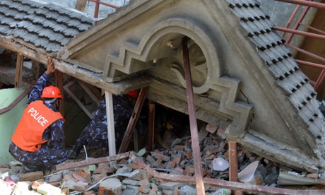 Rescue team officials and a sniffer dog search for survivors at a collapsed house in Kathmandu, Nepal.