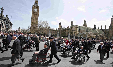 Veterans walking and in wheelchairs passing by Big Ben in a parade