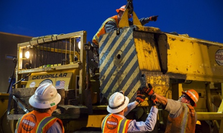 Workers prepare heavy machinery to remove the train.