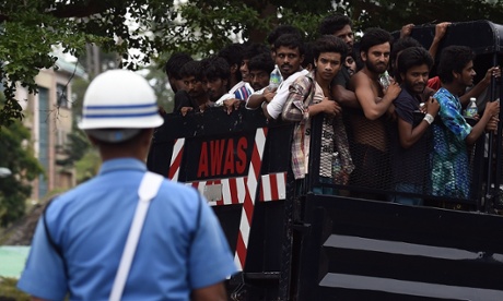 A member of the Malaysian navy stands guard as a truck carrying migrants from a temporary detention centre arrives at a naval base.