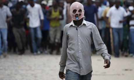 A masked protester walks during a protest against President Pierre Nkurunziza’s decision to run for a third term