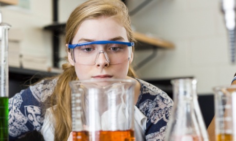 Young scientist peering mournfully at strange-coloured liquid in a beaker 