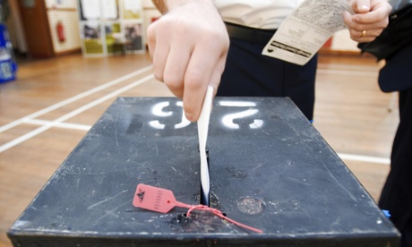 A voter places his voting card into a ballot box