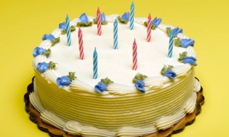 Candles and blue decorative flowers on birthday cake
