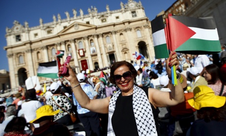 A member of the crowd waves Palestinian flags in Saint Peter's square on Sunday.