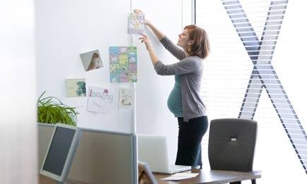A pregnant woman arranges greetings cards at work