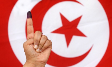 A Tunisian woman raises her ink-stained finger after casting her vote in the country’s first post-revolution presidential election on 23 November 2014.