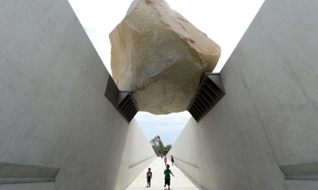 Children take in the view from beneath a giant rock on display at the Los Angeles County Museum of Art (LACMA) in Los Angeles.