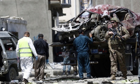 US soldiers stand guard next to a destroyed vehicle hit by a car bomb close to the US military airport gate in Kabul.