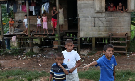 Residents stand outside their home as they watch soldiers unload supplies from a military helicopter for people who suffered damage from Tropical Storm Ida in Bluefields, Nicaragua