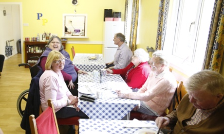 A group of people having lunch together at a line of tables.