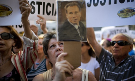A woman chants the Argentine national anthem holding a portrait of the late prosecutor Alberto Nisman outside the AMIA Jewish community center in Buenos Aires, Argentina, in January.