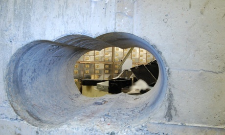 The hole drilled into the wall of the safe deposit vault.