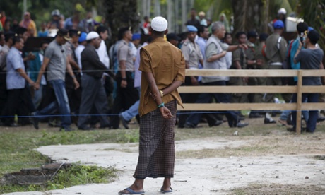 A Rohingya migrant watches as Indonesian officials visit a temporary shelter in Aceh Timur in Indonesia's Aceh province.