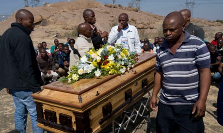 Striking mineworkers stand over the coffin of Mpuzeni Ngxande at the spot where 34 miners were shot dead near Lonmin's platinum Marikana mine.