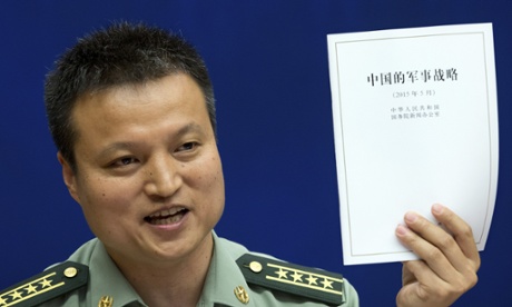 China’s defense ministry spokesman Yang Yujun holds up a report on China’s military strategy unveiled on Tuesday: China has compared its controversial island-building to ordinary infrastructure construction going on elsewhere in the country.