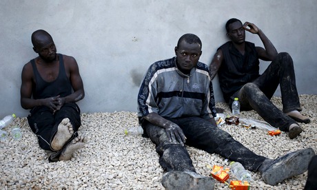 Illegal migrants sit in a coastal police base in Tripoli