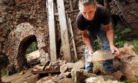 LABOR OF LOVE--Jim Bishop, 57, lifts rocks to load onto a self-made pulley lift to add to a chimney on the castle that he has been building for over 30 years.