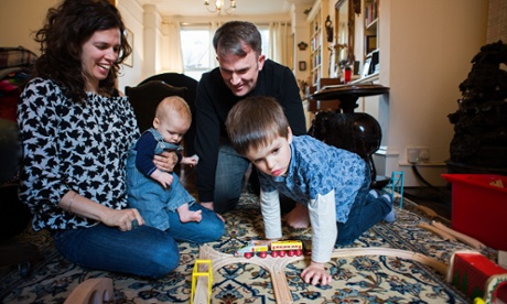 Liz Field and her husband at home with Cian, playing with a train set
