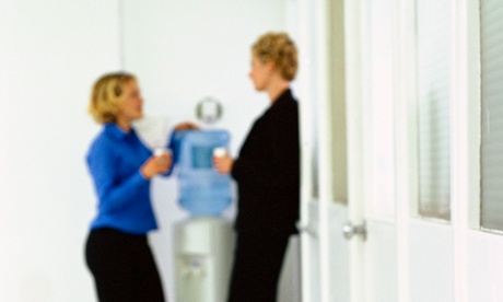 Two women office workers chatting around a water cooler