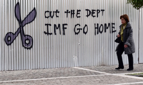 A woman walks past a slogan in central Athens in January. The great wave of hope that had brought Syriza to power has now crashed on the rocks of renewed uncertainty.