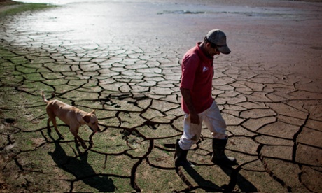 A resident and his dog walk across the drying bottom of the Paraibuna dam, part of the Cantareira water system that provides greater São Paulo with most of its water.