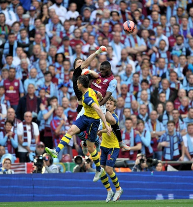 Arsenal keeper Wojciech Szczesny punches the ball while under pressure from Nathan Bake.