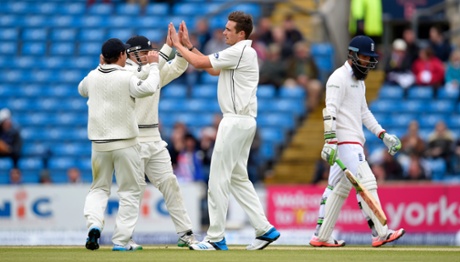 Moeen Ali leaves the field as Tim Southee celebrates with team mates.