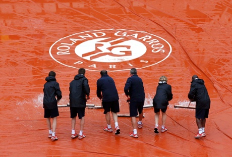 Workers sweep water off a tarp as rain interrupts the women's singles match.