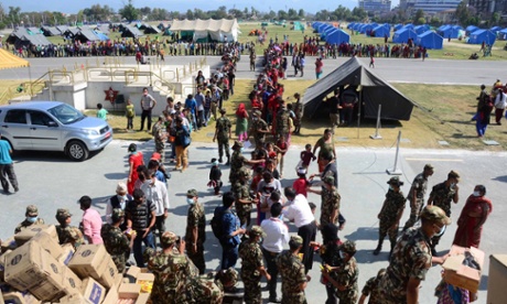 People queue to receive food and water supplies at a temporary shelter in the aftermath of the earthquake in Nepal.