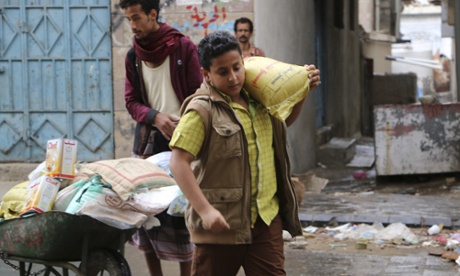 A boy carries a bag of sugar to his family during  food distribution by Yemeni volunteers in Taiz. 