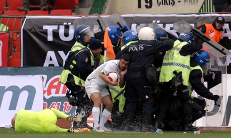 A Bursaspor player hides from the objects thrown by Diyarbakirspor fans, as an injured assistant referee lays on the pitch, during the Super League soccer match in Diyarbakir in March 2010.