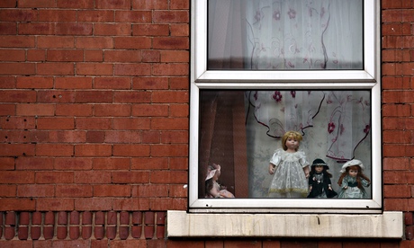 Dolls are displayed in an upper floor window of a house in Rotherham