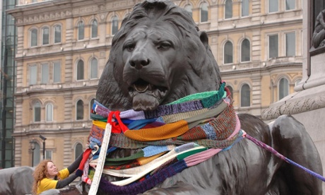 A member of the ‘Stitch and Bitch’ knitting group wrapping giant scarves around a Trafalgar Square lion