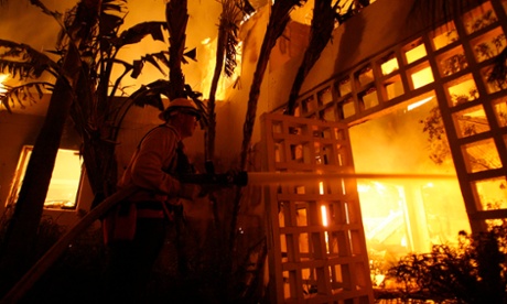 A fireman sprays water on a house burning during the Jesusita wildfire in Santa Barbara, California.
