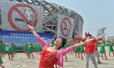 Dancers perform in front of anti-smoking banners displayed on the Beijing National Stadium on World No Tobacco Day on 30 May
