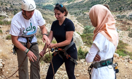 Will Harris of Wadi Climbing helps Summer Rushdi with her belaying technique on a climbing course at Ein Qiniya in the occupied Palestinian territories watched by 16 year Rubaa Bledi who will do her first rock climb a few minutes later.
