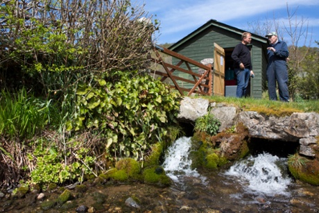 Welsh sheep farmer Howell Williams and Chris Blake of The Green Valleys  stand on the banks of the stream at the base of the farm 15kW hydro power plant on the Brecon Beacons, Wales.